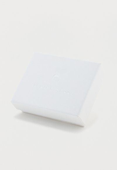 Λευκό ορθογώνιο κουτί με υφή, που φέρει ανάγλυφη επωνυμία "MARINE SERRE" και έναν κυκλικό λογότυπο στην πάνω επιφάνεια.