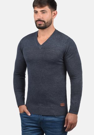 Maglione grigio scuro a scollo a v in un morbido filato, con polsini e orlo a coste, e una piccola etichetta in pelle con logo in vita.