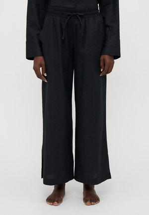 Pantalones anchos negros hechos de lino. Cuentan con una cinturilla elástica con cordón y bolsillos laterales. Con una textura suave y un ajuste relajado.