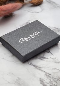 Grå texturerad smyckeslåda med en slät yta. Framsidan visar "Sofia Milani Jewels" i silvermanus. Rektangulär form med en gångjärnslock.