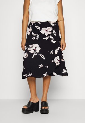 Zwarte bloemenrok met een gerimpelde zoom, met grote crèmekleurige bloemen en subtiele roze accenten. Draagt zwarte platform schoenen.