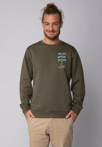 Olijfgroene sweatshirt met lange mouwen, ronde hals en grafische print van richtinggevende houten borden met landschappen en vissen.