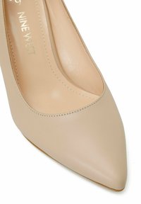Décolleté beige in pelle a punta con una texture liscia e dettagli di cucitura minimi. L'interno è di un colore simile, progettato per l'abbigliamento formale.
