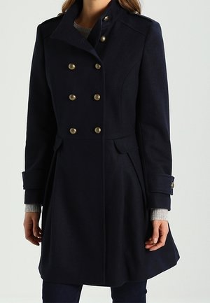 Navy wollen jas met een hoge kraag, dubbelzijdig ontwerp, goudkleurige knopen, zijzakken en een gestructureerde uitstraling. Lange mouwen met manchetten.