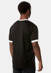 Black athletic t-shirt featuring short sleeves with white accents and a contrasting collar. Smooth fabric and a relaxed fit design.