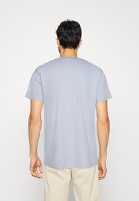 Camiseta de manga corta azul claro, material de algodón, cuello redondo, de color sólido sin patrones, mostrada desde la parte de atrás. Diseño y corte simples.
