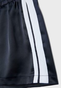 Mornarsko modro blago z dvema vertikalnima belima progama in tanko črno črto na sredini, ki prikazuje del oblačila z elastičnim pasom.