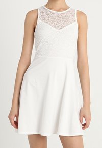 Bílé šaty s krajkovým korzetem a bezrukávovým designem. Rozšířená sukně pro pohodlný střih. Měkká látka s hladkým povrchem.