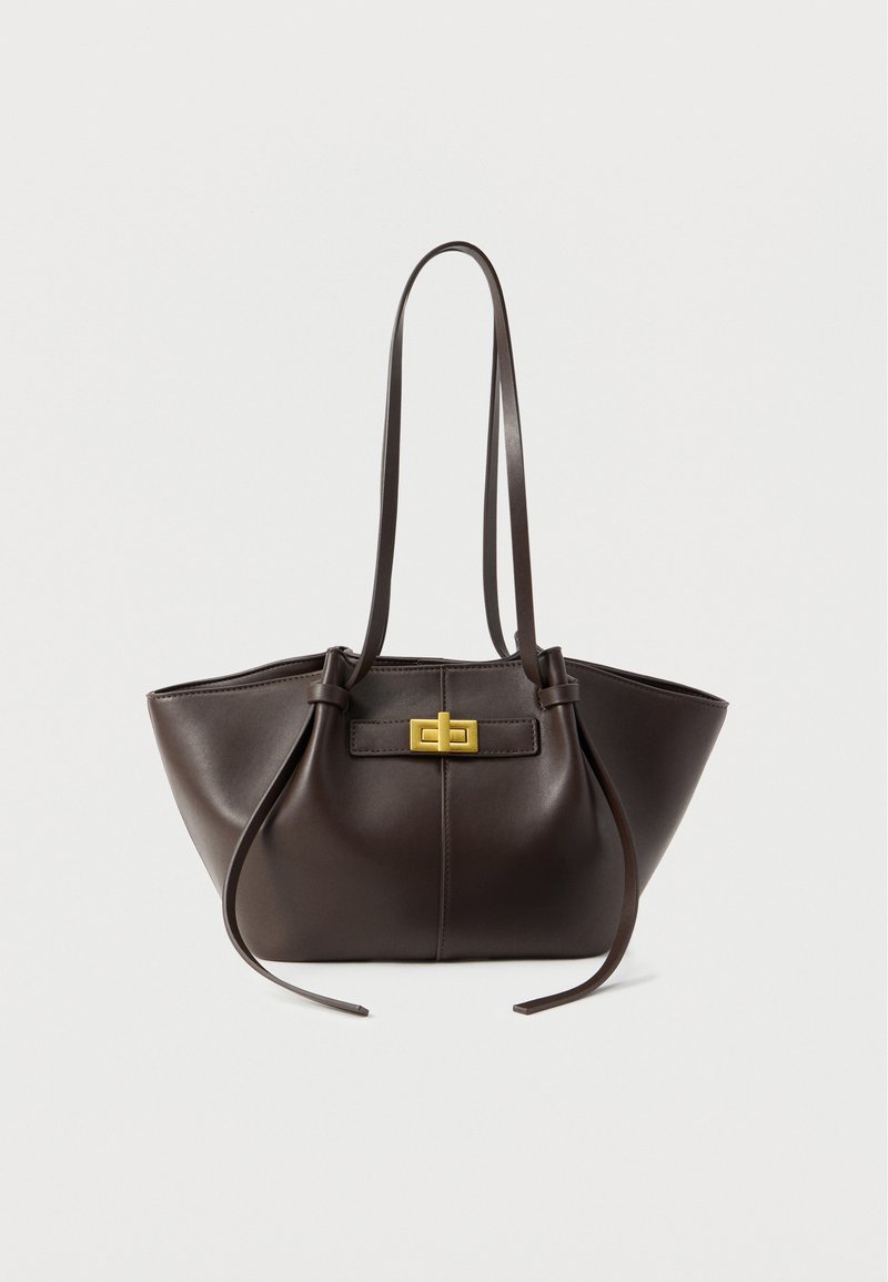 Σκούρα καφέ δερμάτινη γυναικεία τσάντα με δύο μακριές λουριά ώμου και χρυσό ορθογώνιο κούμπωμα με στριφογυριστό κλείσιμο μπροστά.