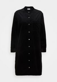 Czarna sukienka koszulowa z korduroy o okrągłym dekolcie, długich rękawach i zapięciu na guziki. Posiada jedną kieszeń na piersi i subtelną teksturę.