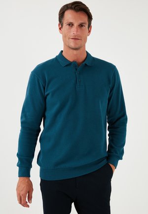 Teal Langarm-Polohemd mit Kragen, Knopfleiste mit drei Knöpfen und gerippten Bündchen. Glatte Textur und taillierte Passform.