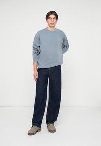 Gray crewneck sweatshirt, dark denim wide-leg pants, and beige shoes. Simple design, soft texture, and solid colors with no patterns.