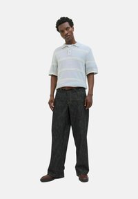 Lys blå strikket polo med korte ærmer og stribede mønstre, parret med mørke vide jeans og brune sko.