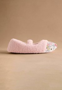 Pantofole foderate in pile rosa con punta arrotondata e parte anteriore in cotone a motivo floreale. Texture morbida, dettagli minimi e un piccolo fiocco decorativo.