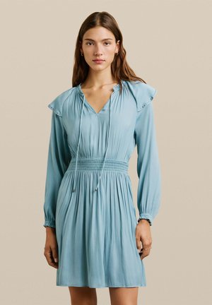 Vestido azul claro con hombros acampanados, escote en V profundo y cintura fruncida. Mangas largas con puños fruncidos, textura de tela suave.