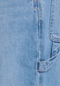 Jasnoniebieska tkanina dżinsowa z widocznym szwem, brzegiem kieszeni i częścią szlufki na pasku na odzieży.