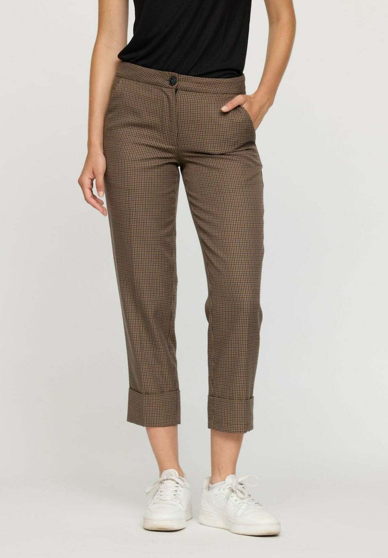 Pantalons à carreaux marron avec une coupe ajustée, ourlets à revers, deux poches avant et fermeture à bouton. Associé à des baskets blanches.