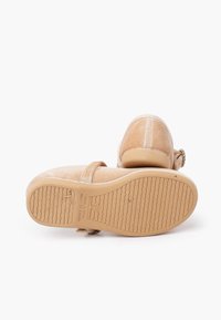 Scarpe Mary Jane beige per bambini con suole in gomma, cinturini in velcro e taglia 26 impressa sulla suola, su uno sfondo bianco.