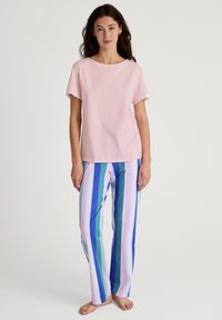 Roze katoenen top met korte mouwen en kantafwerking, gecombineerd met meerkleurige gestreepte broek in blauw, groen, roze en wit. Lichtgewicht en ontspannen pasvorm.