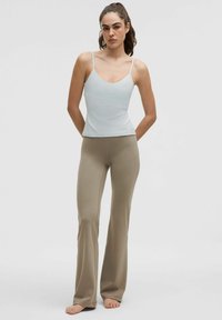 Light blue fitted tank top with thin straps paired with beige flared pants. Smooth texture, minimal design, and neutral color palette.