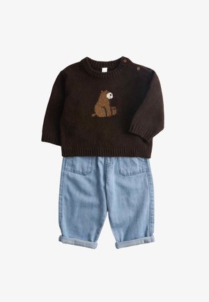 Brown knitted sweater with a bear design on the front and denim rolled-up pants, featuring pockets and a relaxed fit.