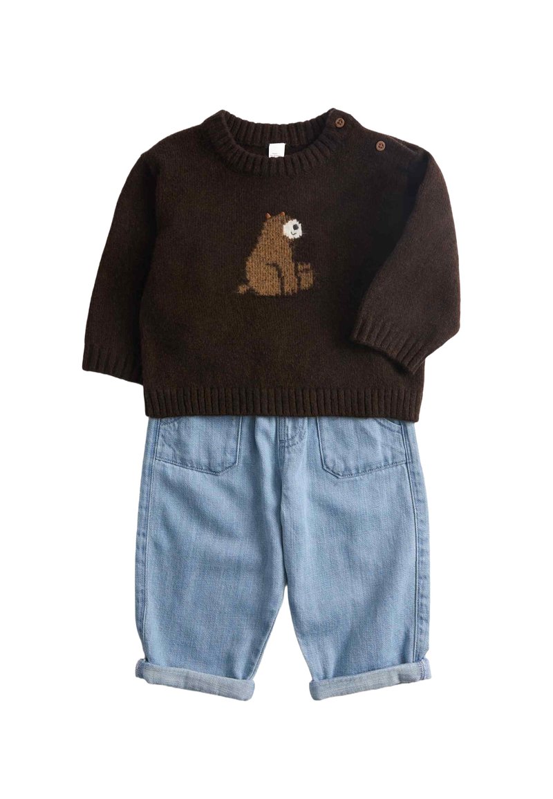 Brązowy dziergany sweter z motywem niedźwiedzia z przodu oraz dżinsowe, podwinięte spodnie z kieszeniami i luźnym krojem.