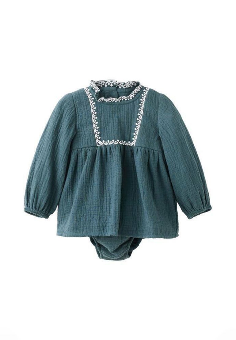 Zelena muslin haljina s dugim rukavima, nabranim ovratnikom i bijelim izvezenim detaljima. Ima skupljeni struk i integrirani donji dio.