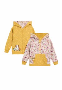 Felpa gialla con zip, decorata con un motivo a pois e accenti floreali; presenta un grafico di un porcellino d'India e un rivestimento interno floreale colorato.