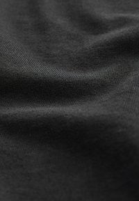 Black cotton fabric with a smooth texture and subtle stretch, displaying soft folds and slight sheen. Close-up view of the material's weave.