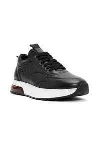 Sneaker in pelle nera con punta tonda, colletto imbottito, lacci neri, suola intermedia bianca e accento trasparente rosso sul tallone.