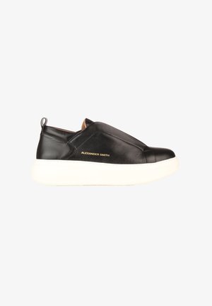 Baskets slip-on en cuir noir avec une semelle blanche épaisse et le logo "Alexander Smith" doré sur le côté.