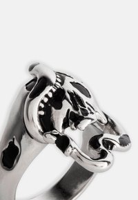 Zilveren ring met een schedelontwerp en zwarte accenten. De vorm is gedetailleerd, met ingewikkelde texturen en gladde krommingen.