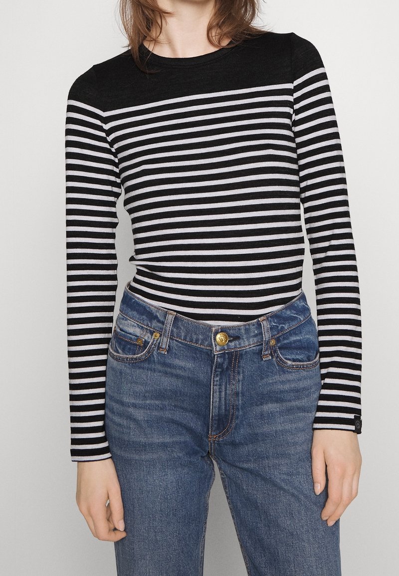 Sort-hvide stribede langærmede skjorte med rund halsudskæring, parret med højtaljede blå denim jeans med knaplukning foran.