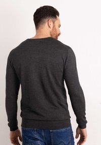Maglione grigio scuro a maniche lunghe realizzato in un morbido tessuto a maglia, con colletto e polsini a costine, design aderente e una superficie posteriore liscia.