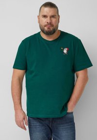 Grünes Baumwoll-T-Shirt mit kurzen Ärmeln, mit einem bestickten Snoopy in einem roten Hut, der eine Trompete hält, und musikalischen Noten nahe dem Halsausschnitt.