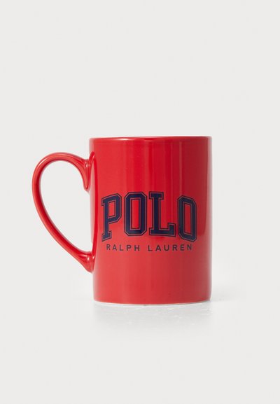 Sarkans keramikas krūze ar izliekto rokturi, uz kuras priekšpuses lieliem tumši zilajiem burtiem ir rakstīts "POLO RALPH LAUREN". Gluda, spīdīga apdare.