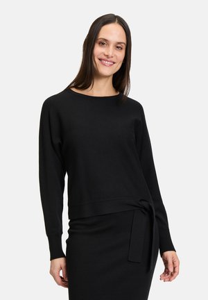 Pull noir à manches longues en tricot doux, avec une coupe ample, un large décolleté et un accent noué à la taille. Texture lisse.