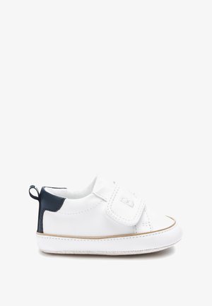 Sneaker en cuir blanc avec des accents bleu marine, une sangle Velcro, une pointe ronde et une semelle texturée. Dispose d'une boucle à l'arrière pour un enfilage facile.