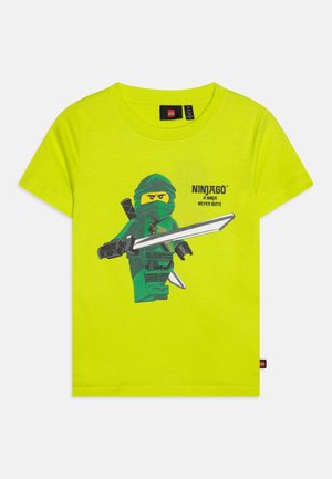 T-shirt enfant jaune-vert vif avec un personnage Lego Ninjago tenant une épée avec le texte "Ninjago Un ninja n’abandonne jamais."
