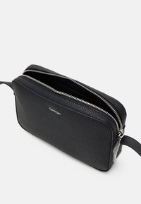 Borsa in pelle nera con finitura testurizzata, chiusura con doppia zip e una piccola cinghia. Presenta un logo sottile sulla parte anteriore e dettagli in metallo argentato.