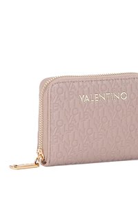 Portafoglio in pelle di colore rosa chiaro con motivo logo in rilievo, chiusura con zip dorata e dettagli in metallo dorato. Forma rettangolare.