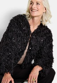 Zwarte textuurjasje met een schappele, bontachtige uitstraling, voorzien van pailletten en een cropped ontwerp, aangevuld met een eenvoudige ronde nek.