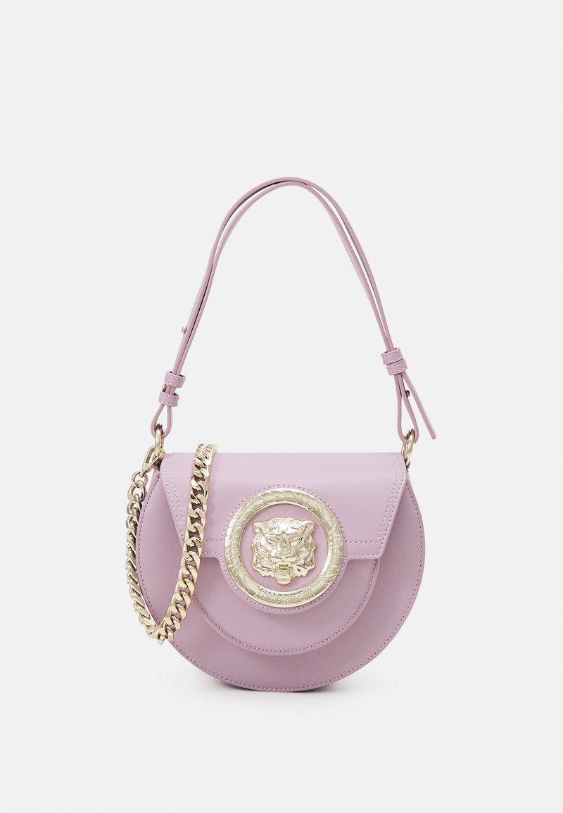 Borsa a tracolla in pelle lilla con un medaglione circolare dorato a forma di leone e una tracolla intrecciata. Presenta una chiusura a patta e una forma arrotondata.
