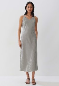 Schwarz-weiß karierter Midi-Kleid mit V-Ausschnitt und dünnen Trägern, aus glattem Material gefertigt. Verfügt über einen geraden Schnitt und einen dezenten Schliff am Saum.
