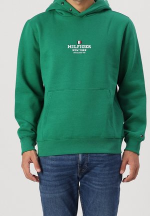 Sudadera con capucha verde, con un bolsillo frontal y puños acanalados. Presenta un logo blanco de "HILFIGER NEW YORK". Está hecha de una tela suave.