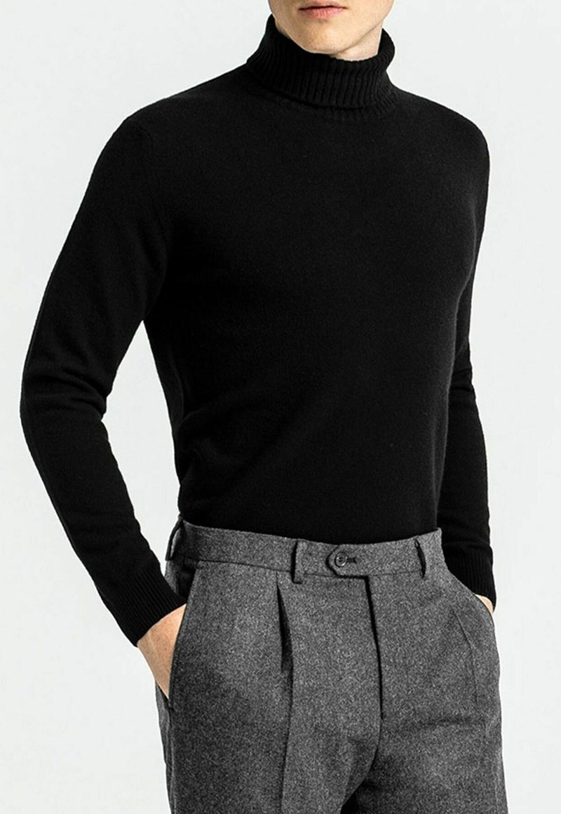 Schwarzer Rollkragenpullover mit geripptem Kragen und taillierter Passform, kombiniert mit grauen, taillierten Hosen mit Falten und Knopfverschluss. Weiche Textur.