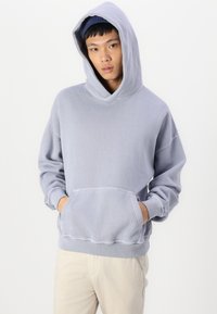Hoodie en pull léger en gris, fabriqué à partir d'un tissu doux, doté d'une grande poche avant, de poignets côtelés et d'une capuche doublée.