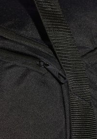 Bolsa de tela texturizada negra con un tirador de cremallera negro y una correa gruesa tejida de color negro que la cruza.