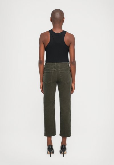 Dark green corduroy pants with a straight cut, featuring back pockets and a mid-rise waistband. Worn with a black tank top and heeled shoes.