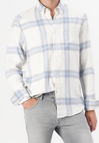 Lichtgewicht geruit overhemd in crème en blauw, voorzien van een button-down kraag, lange mouwen en een borstzak. Gecombineerd met grijze jeans.